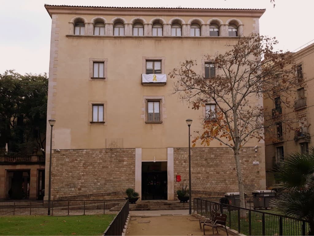 Fachada del Ayuntamiento de Ciutat Vella, con planta baja de piedra y galería de arcos en la cornisa.